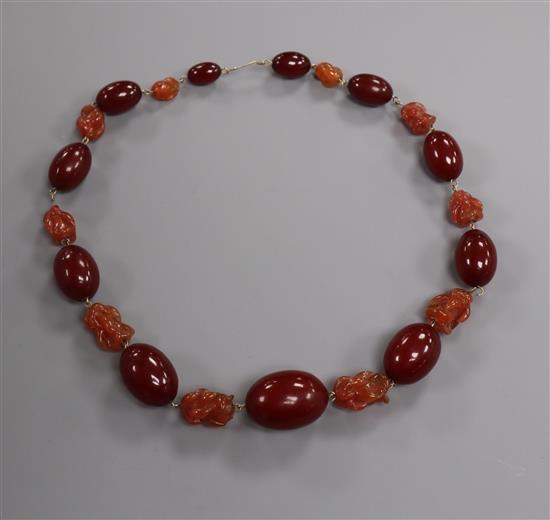 A single strand graduated simulated cherry amber bead necklace with carved paste spacers, 50cm.
